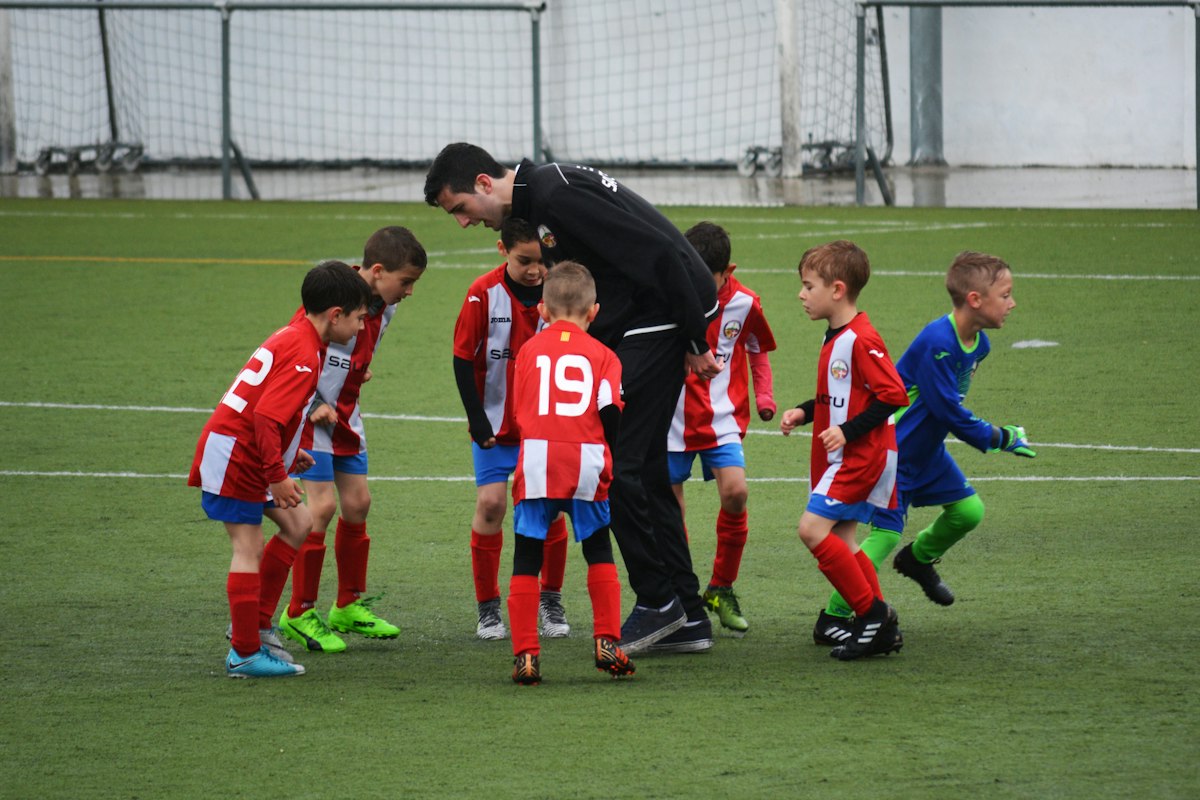 A youth soccer coach huddled with his team on the field