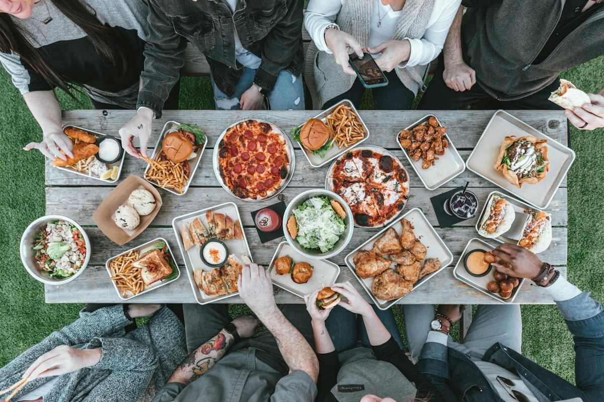 Friends sharing a long table full of food, seen from above